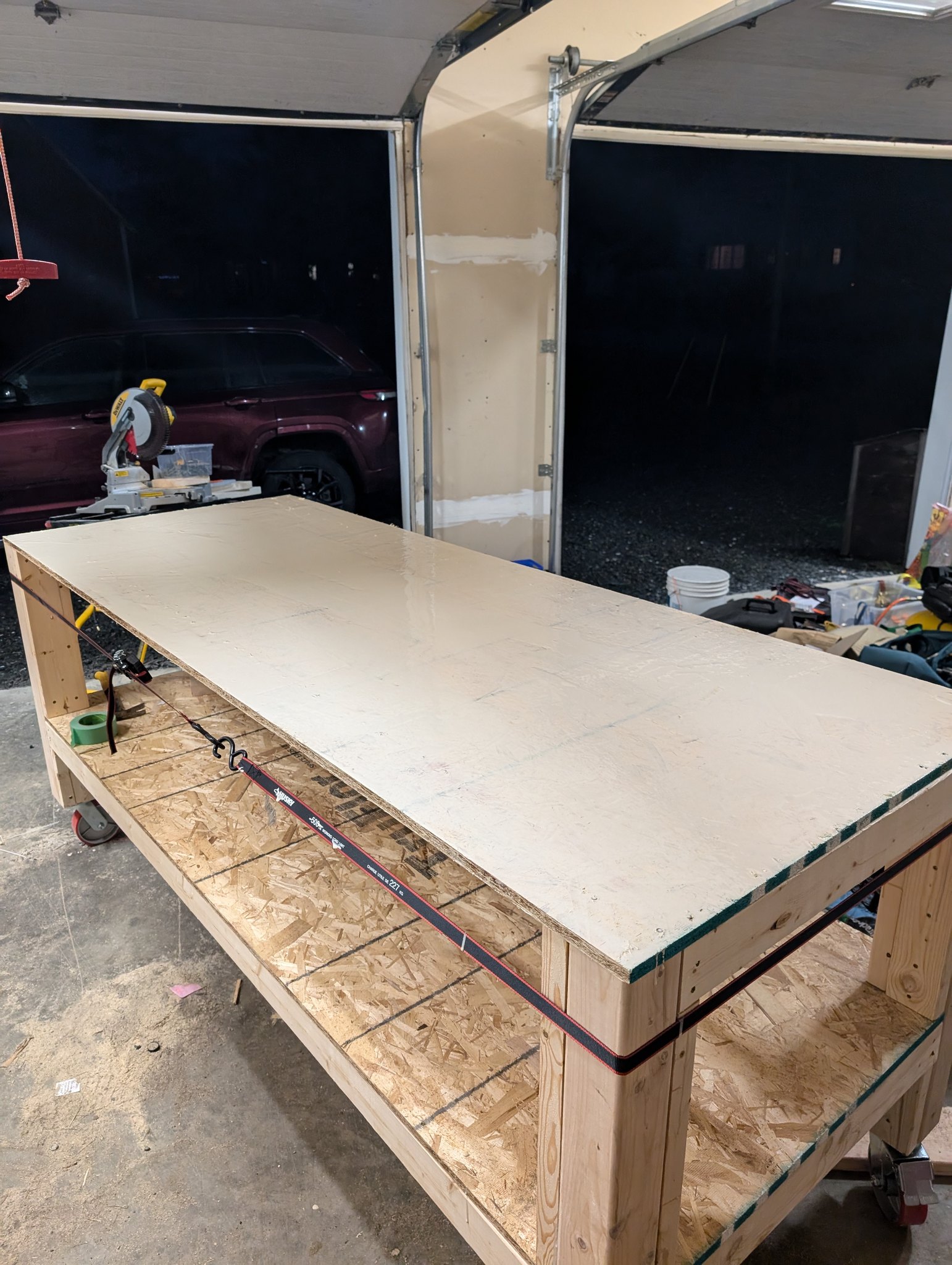 Assembled timber workbench with a smooth worktop, OSB lower shelf, and casters